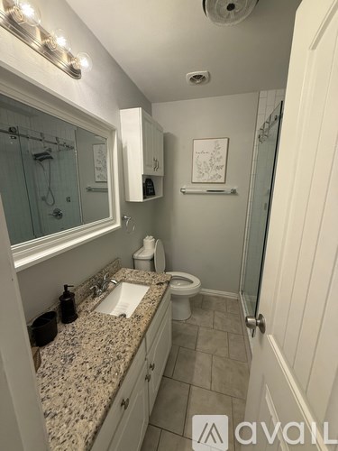 A bathroom with granite countertops and a glass shower door.