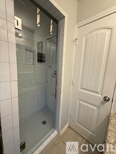 A white door is next to a glass shower stall.