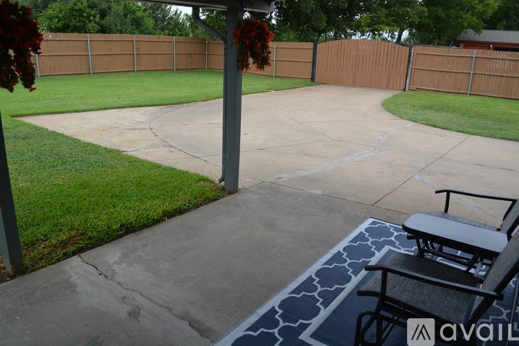 A patio with a table and chairs and a fence in the background.
