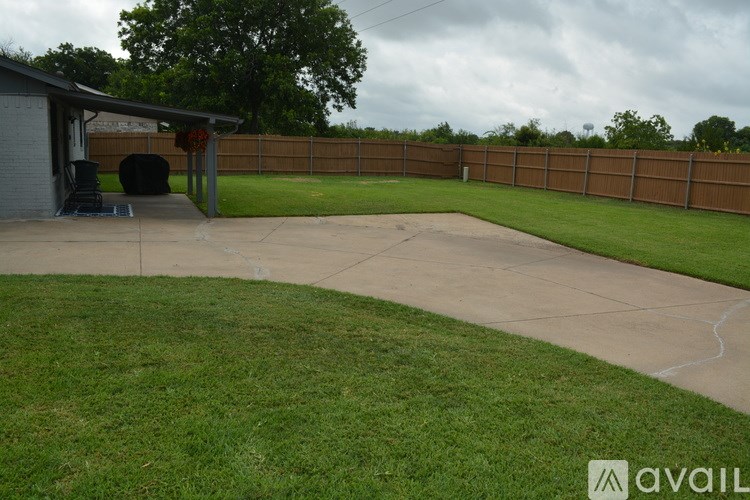 A backyard with a concrete patio and a wooden fence.