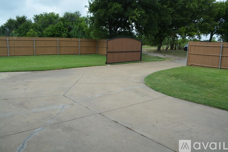 A brown fence encloses a green lawn and a concrete patio.