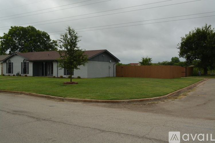 A house with a brown fence and a tree in front of it.