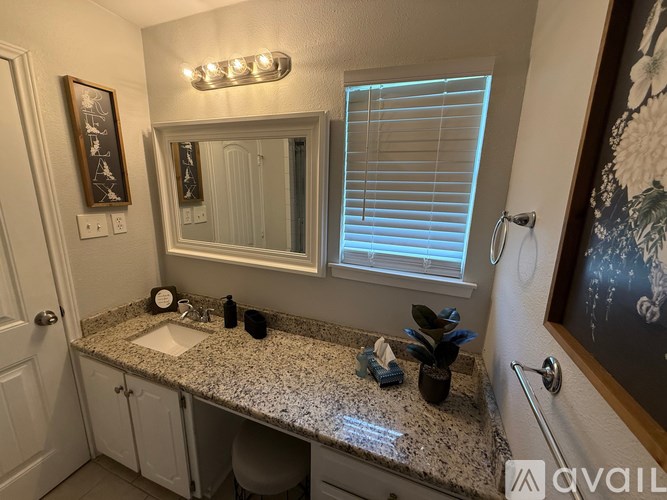 A bathroom with granite countertop and a large mirror.