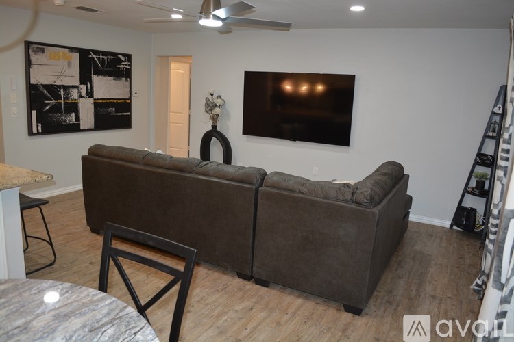 A living room with a brown couch and a black and white painting on the wall.