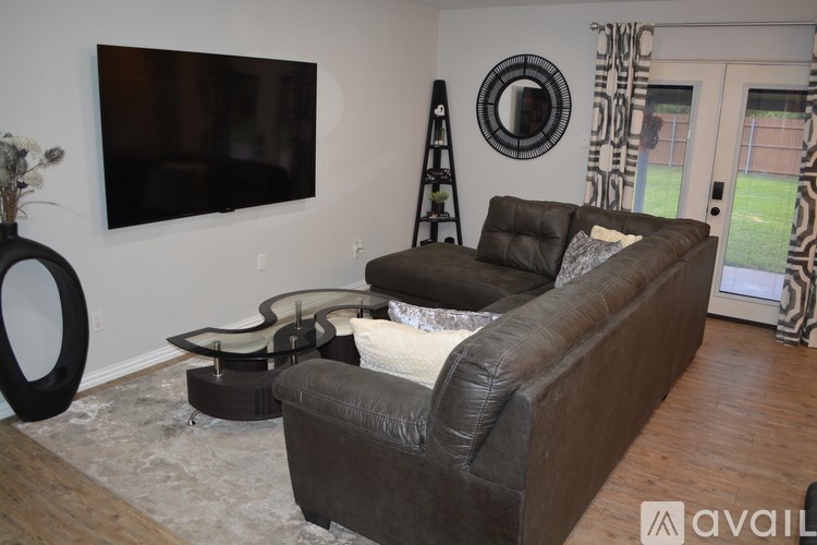 A living room with a brown couch and a flat screen TV mounted on the wall.