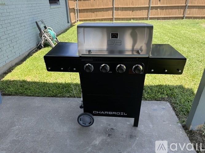 A black Charbroil portable grill with a lid and four burners is on a concrete surface outside.