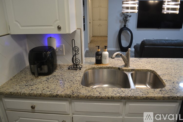 A kitchen counter with a sink, a toaster, and a bottle of soap.