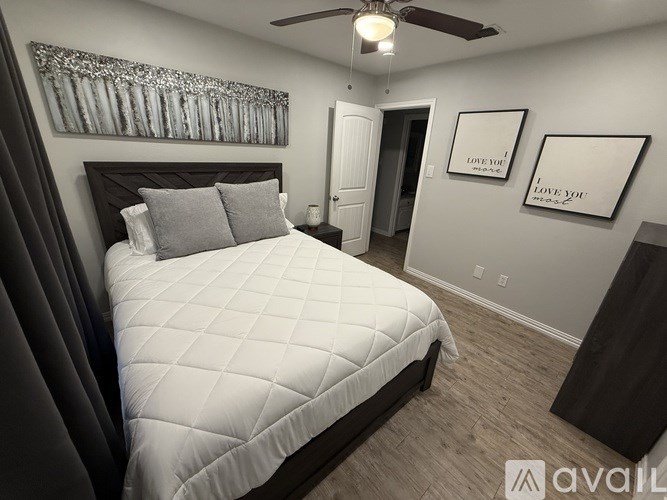 A bedroom with a large bed and two pictures on the wall.