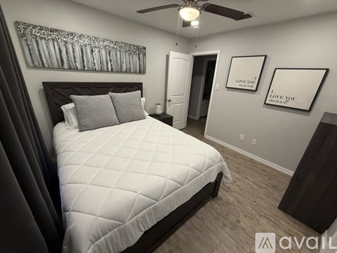 A bedroom with a large bed and two pictures on the wall.