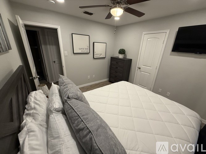 A bedroom with a bed, dresser, and ceiling fan.