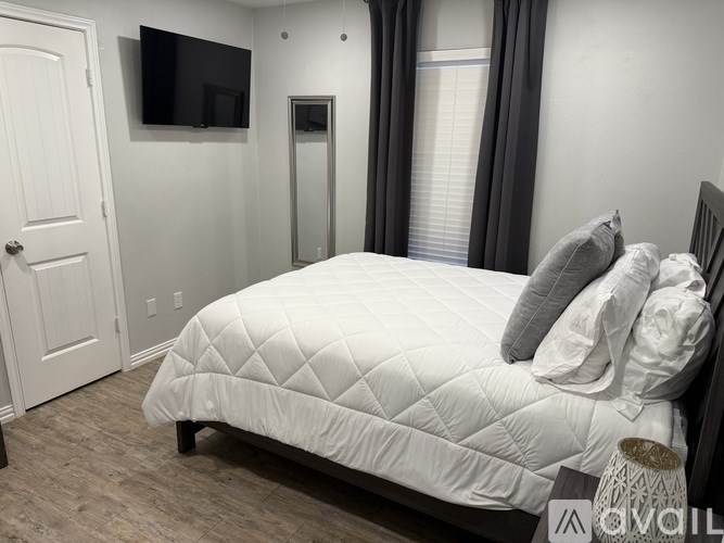 A bedroom with a bed, a television, and a door.