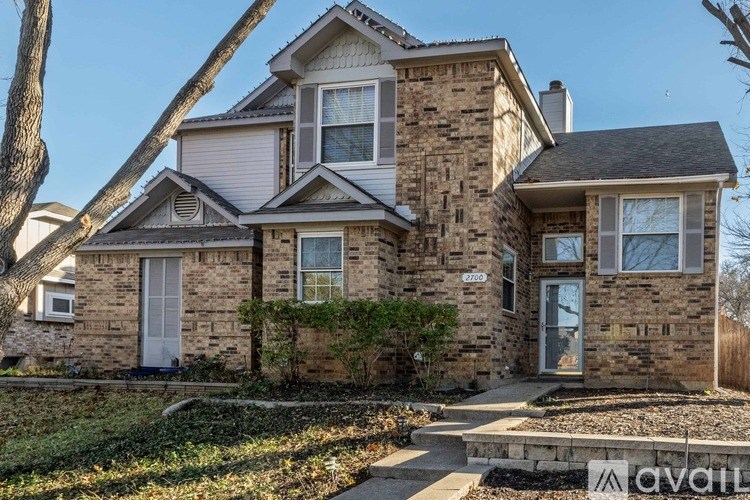 A two-story house with a stone facade and a large front yard.