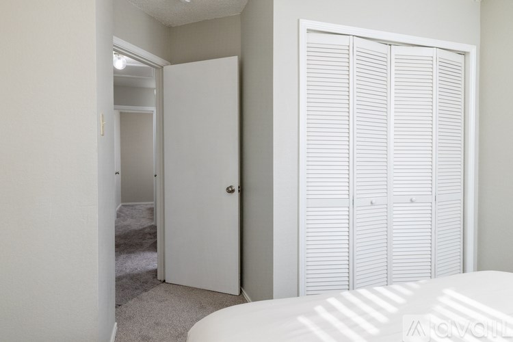 A white bedroom with a white bed and a white wardrobe.