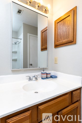 A bathroom with a white counter top and wooden cabinets.