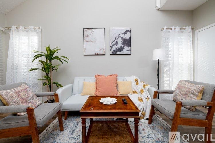 A living room with a grey couch, a wooden coffee table, and a plant.