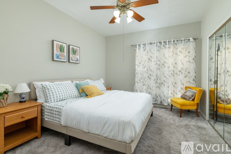 A bedroom with a bed, a chair, and a ceiling fan.