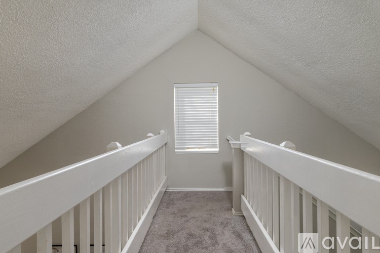 A white balcony with a carpeted floor and a window with blinds.