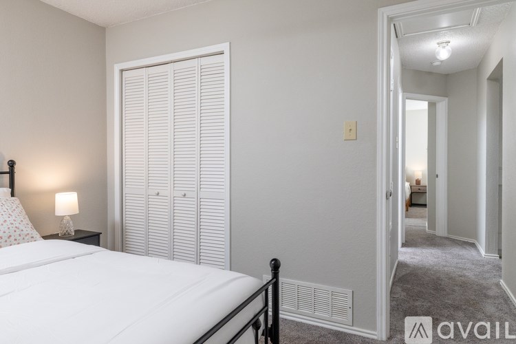 A bedroom with a bed, nightstand, and a window with blinds.