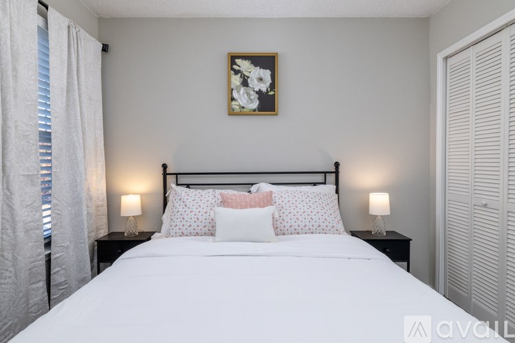 A bedroom with a large bed, two lamps, and a framed picture on the wall.