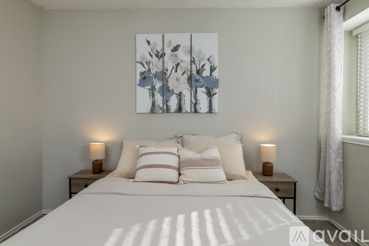 A bedroom with a large bed, two nightstands, and a painting on the wall.