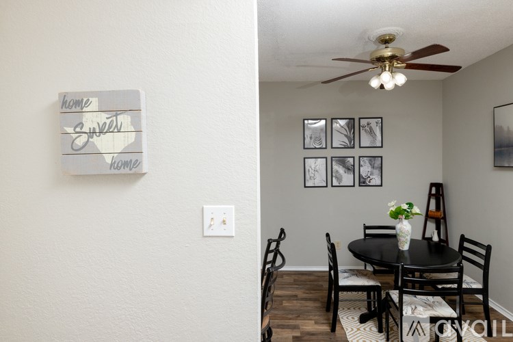 A dining room with a table set for two and a wall with pictures.