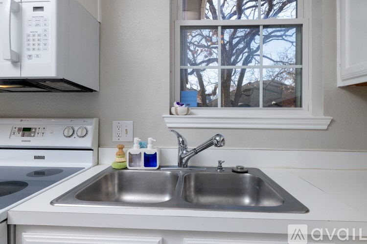 A kitchen with a stove, sink, and window.