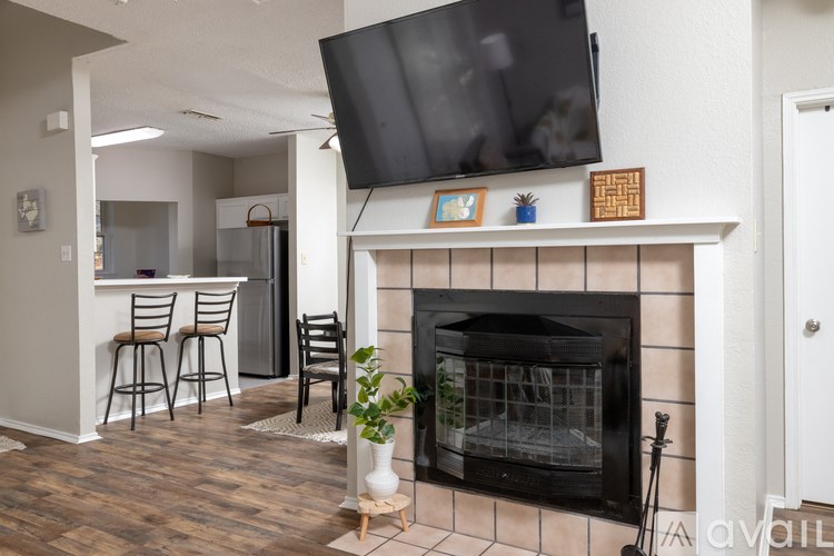 A living room with a fireplace and a television mounted above it.