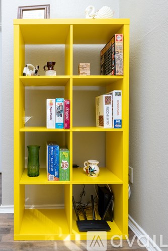 A yellow bookshelf with various books and decorative items.
