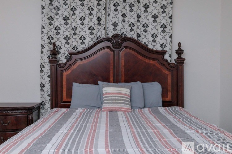 A bed with a wooden headboard and striped bedspread with two blue pillows.