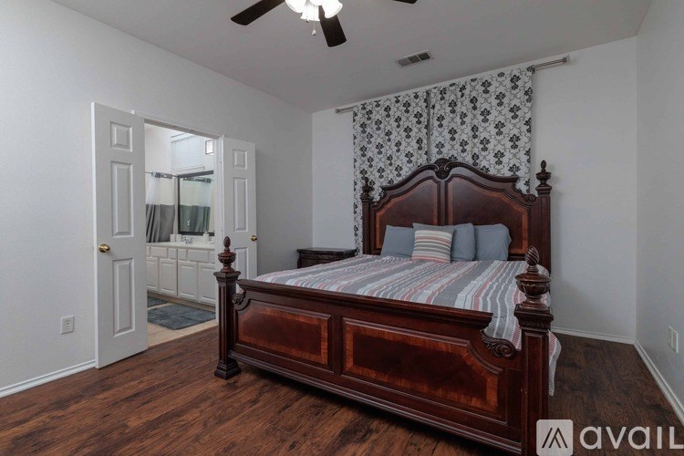 A bedroom with a large bed and a ceiling fan.
