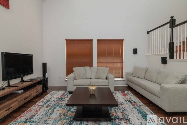 A living room with a white couch, a coffee table, and a television.