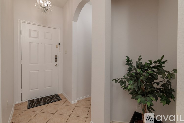 A hallway with a white door and a plant on the right side.