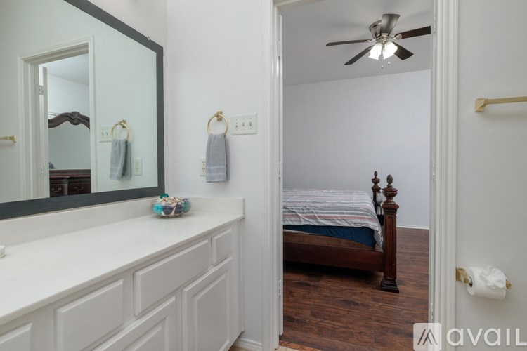 A bedroom with a bed, dresser, mirror, and ceiling fan.