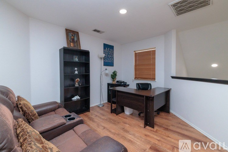 A living room with a brown couch and a black bookshelf.