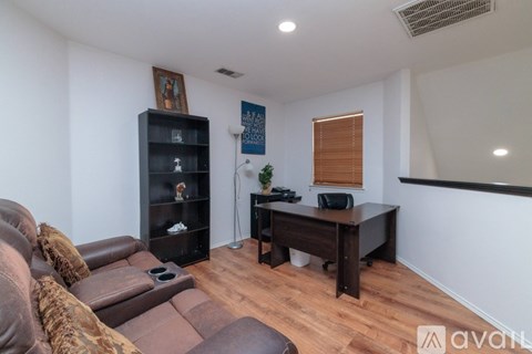 A living room with a brown couch and a black bookshelf.