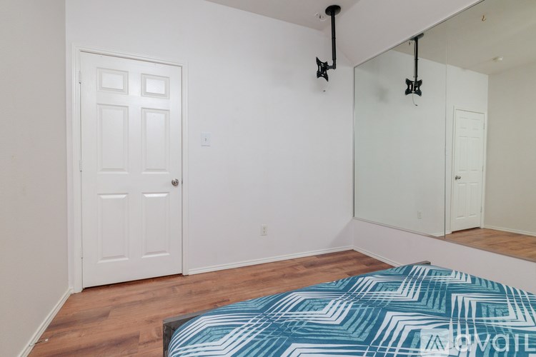 A bedroom with a bed, mirror, and door.