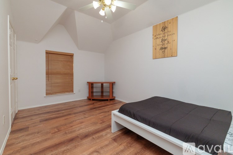 A bedroom with a bed, wooden floors, and a wooden sign on the wall.