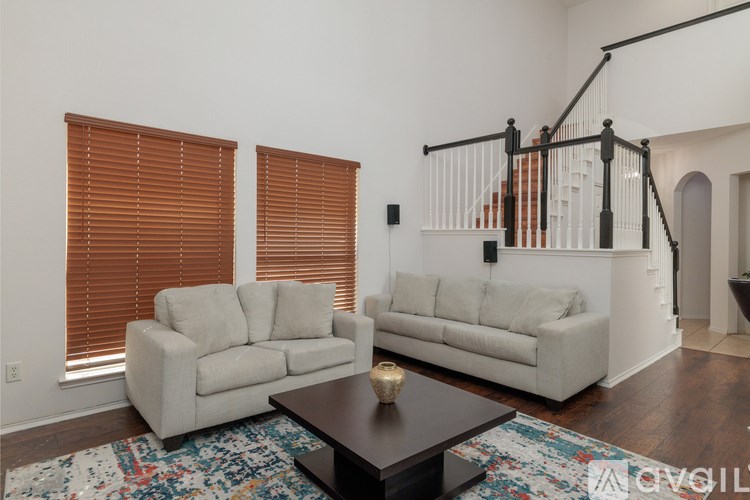 A living room with a white couch, a coffee table, and a staircase.