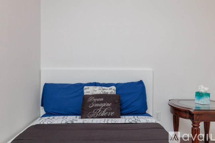 A bed with a blue pillow and a sign that says "Dreams are free" on it.