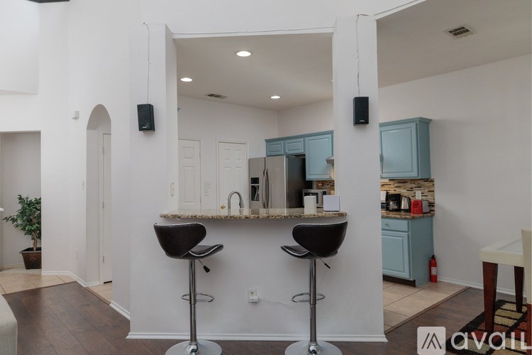 A kitchen with a bar area featuring two black bar stools.