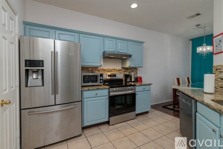 A kitchen with blue cabinets and a stainless steel refrigerator.