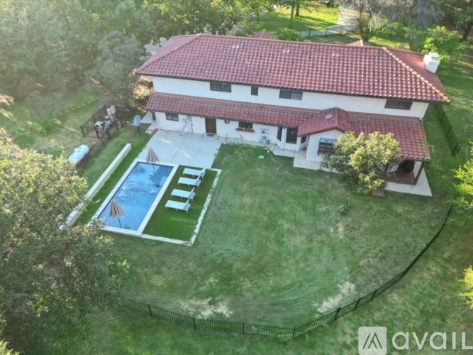 A house with a red roof and a pool in the backyard.