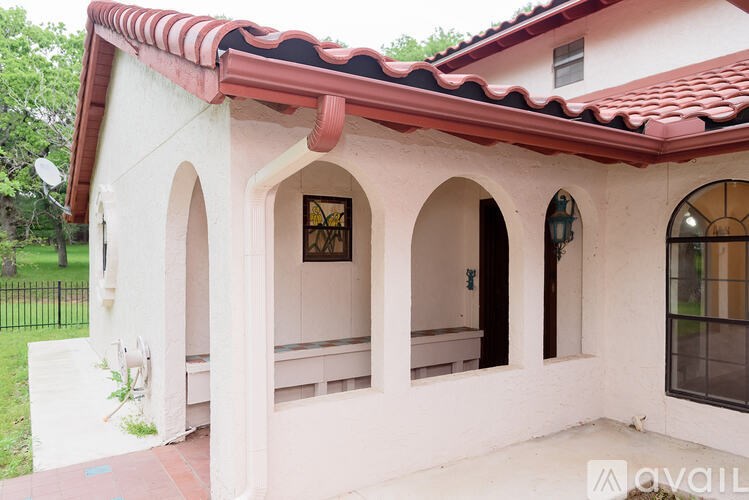 A house with a red tile roof and white walls with arched windows and doors.