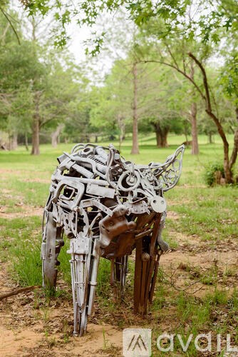 A sculpture of a horse made from scrap metal parts is in a field.