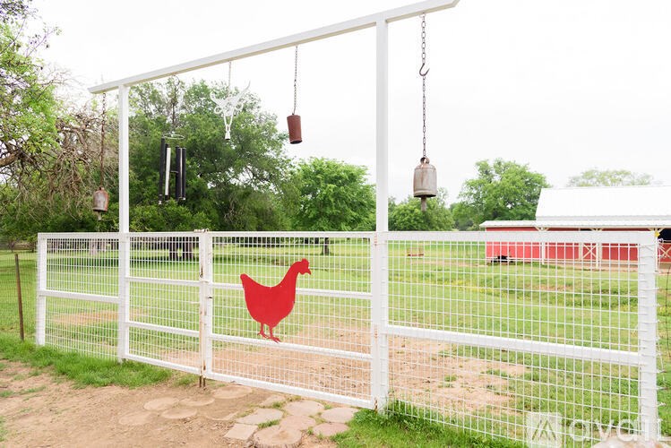 A white fence with a red chicken hanging on it.