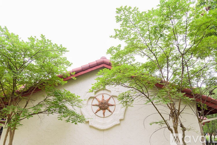 A building with a red roof and a decorative sun design on the wall.