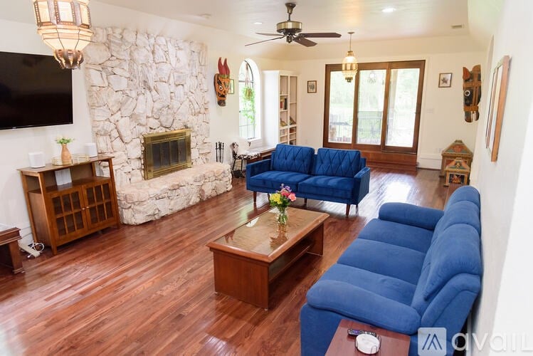 A living room with a stone fireplace and blue couches.