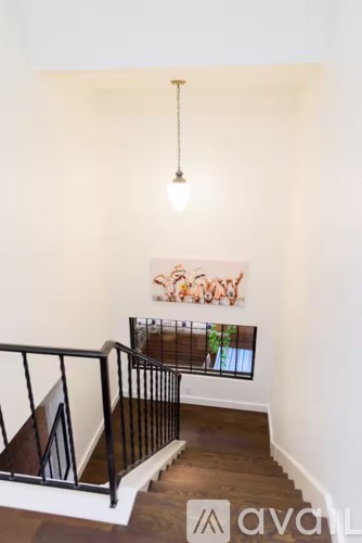 A staircase with a black railing and a light hanging from the ceiling.