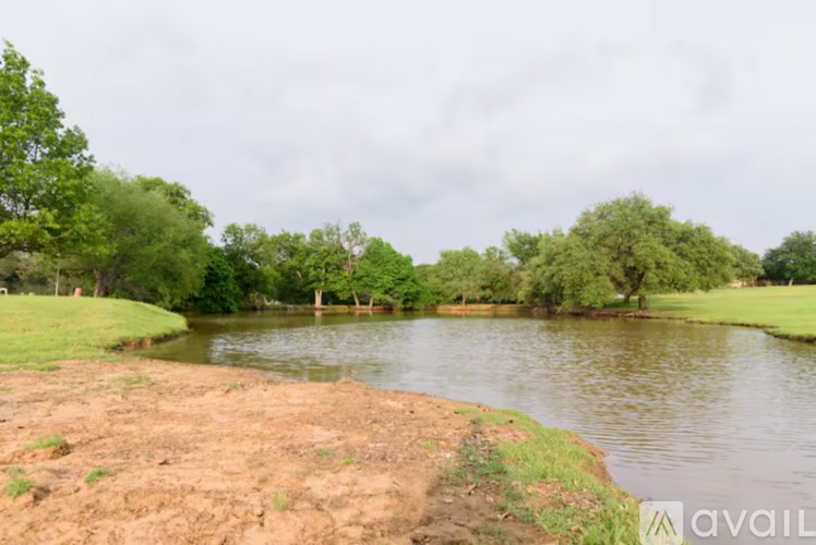 A body of water surrounded by greenery and a cloudy sky.
