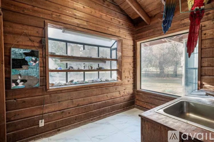 A wooden cabin with a window overlooking a field.